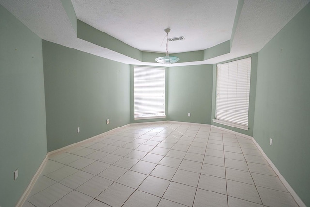 empty room featuring a textured ceiling, visible vents, and light tile patterned floors