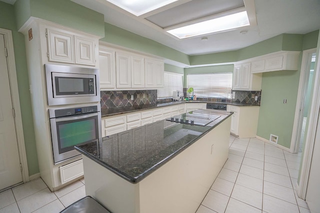 kitchen with backsplash, light tile patterned flooring, stainless steel appliances, and white cabinetry
