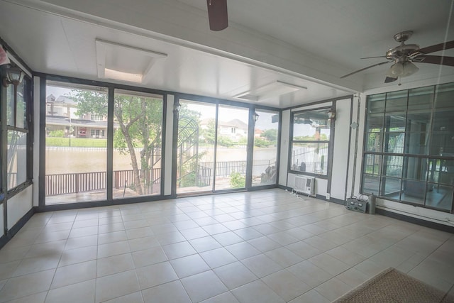 unfurnished sunroom with a ceiling fan, tile patterned floors, and floor to ceiling windows