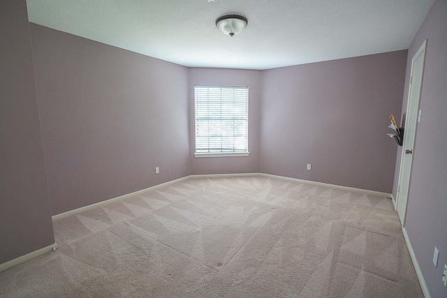 unfurnished room with a textured ceiling, baseboards, and light carpet