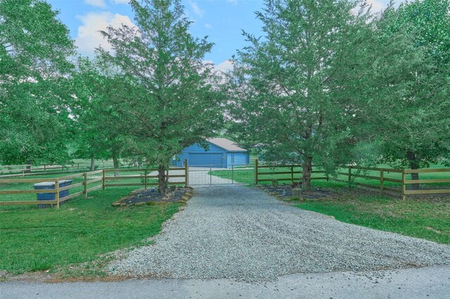 27548 N Log Cabin Rd, Montgomery, TX 77356 - obstructed view of property featuring an outdoor structure, a garage, gravel driveway, and a gate