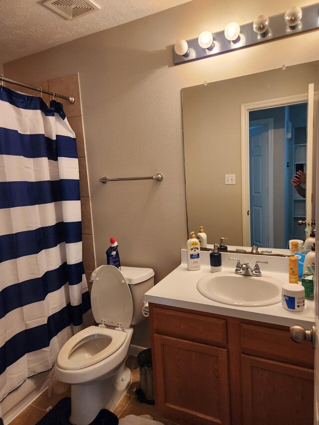 bathroom with a textured ceiling, vanity, curtained shower, toilet, and visible vents