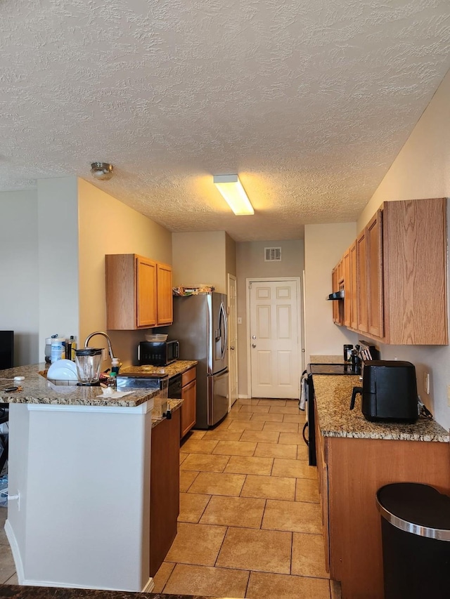 kitchen featuring brown cabinets, electric range, a peninsula, a textured ceiling, and stainless steel refrigerator with ice dispenser