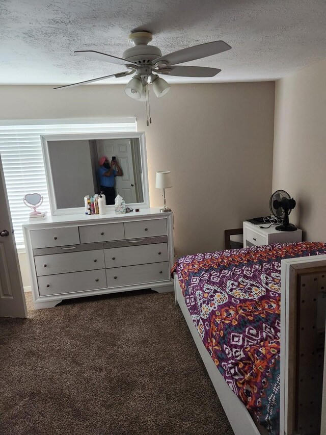 bedroom featuring dark carpet, a textured ceiling, and ceiling fan