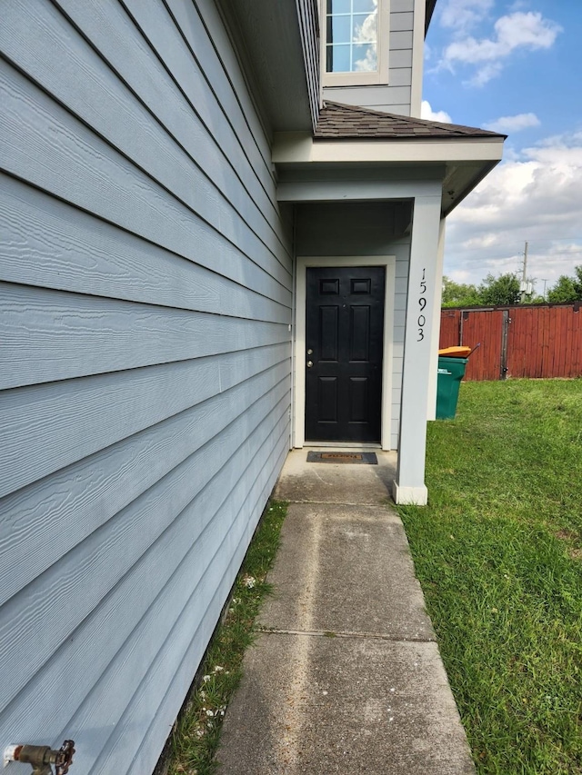 property entrance featuring a yard and fence