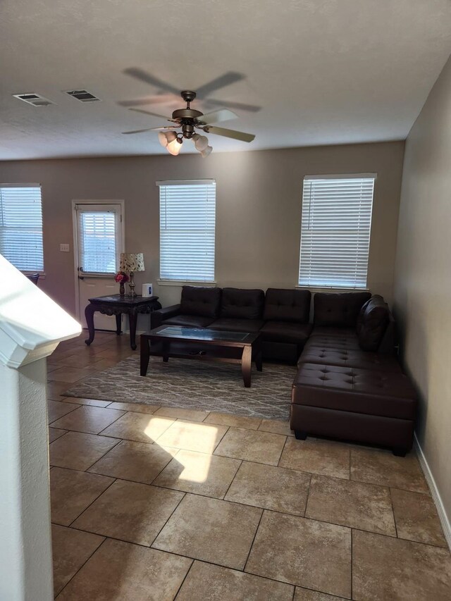 living area with visible vents, a ceiling fan, and baseboards