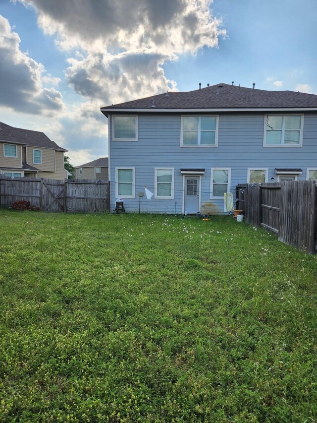 rear view of house featuring a fenced backyard and a yard