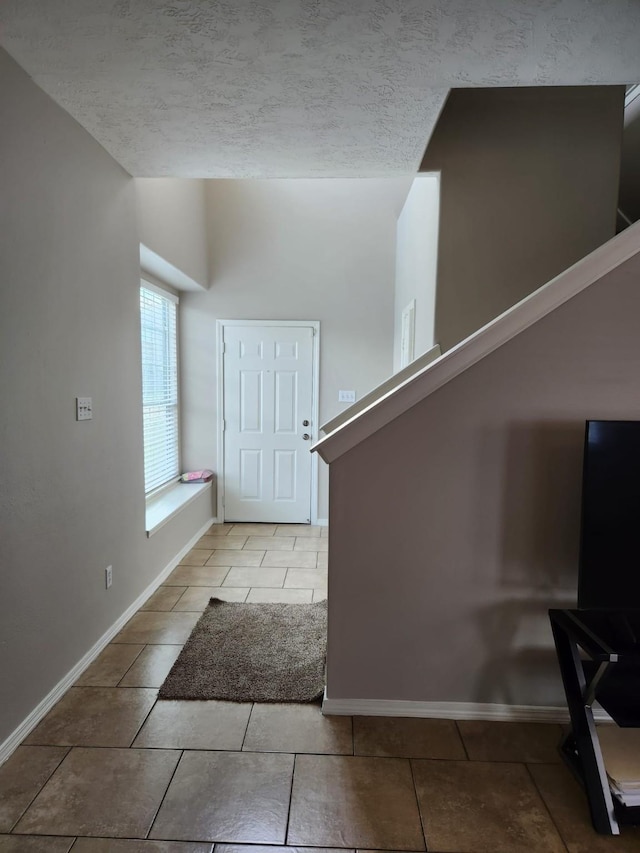 entrance foyer featuring a textured ceiling, tile patterned flooring, and baseboards