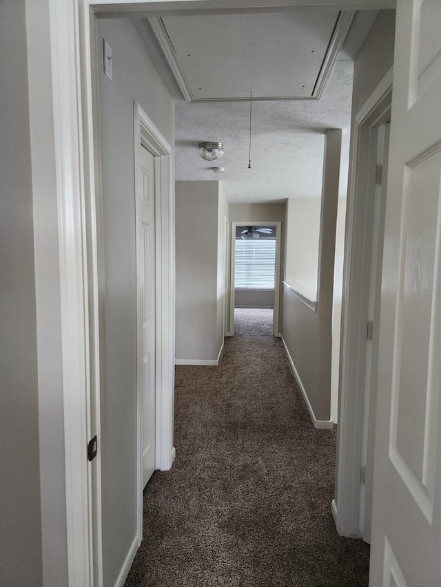 hallway featuring attic access, baseboards, and carpet