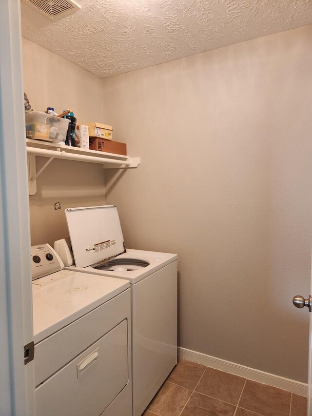 clothes washing area with tile patterned floors, a textured ceiling, laundry area, visible vents, and independent washer and dryer