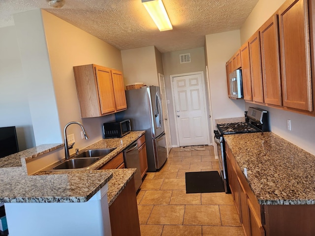 15903 Winston Point Ln, Houston, TX 77084 - kitchen with appliances with stainless steel finishes, a sink, a peninsula, a textured ceiling, and dark stone countertops