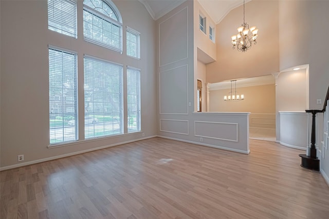 4530 Lakeside Meadow Dr, Missouri City, TX 77459 - unfurnished living room featuring a chandelier, a towering ceiling, crown molding, light wood-style floors, and baseboards