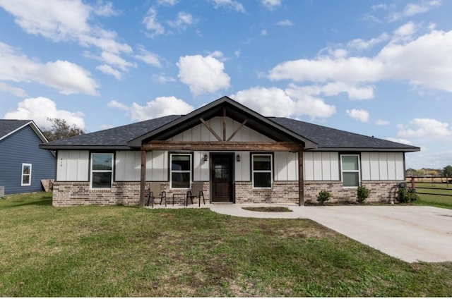 418 E St, East Bernard, TX 77435 - view of front of home featuring board and batten siding, a front lawn, brick siding, and fence