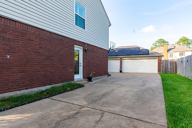view of side of property with brick siding, fence, a yard, and a detached garage