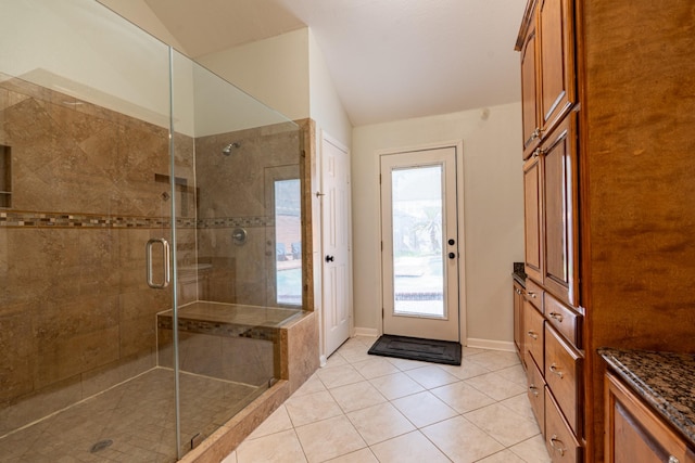 bathroom featuring vaulted ceiling, a shower stall, tile patterned floors, and baseboards