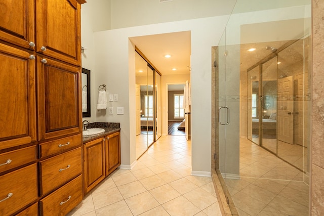 ensuite bathroom featuring tile patterned floors, baseboards, a shower stall, vanity, and connected bathroom
