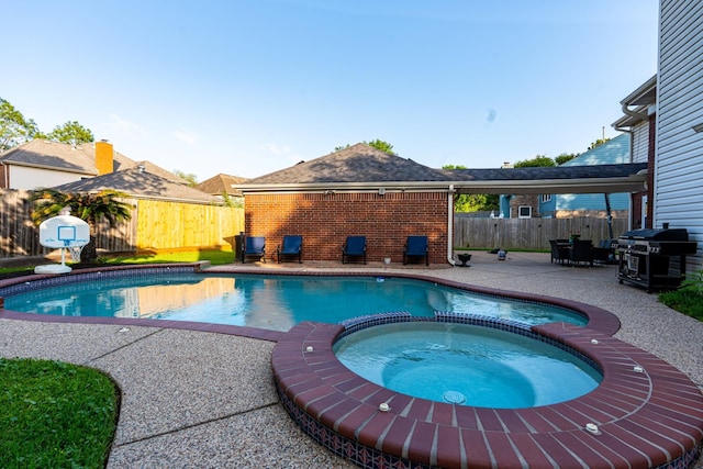 view of pool featuring a pool with connected hot tub, a patio, a fenced backyard, and grilling area