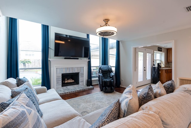 living room with ornamental molding, visible vents, wood finished floors, and a fireplace
