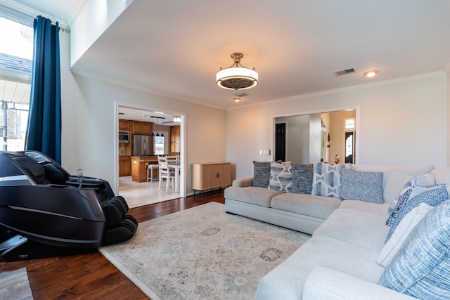 living area featuring visible vents, wood finished floors, and crown molding