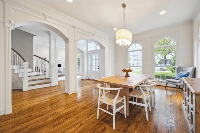 dining space with recessed lighting, stairway, wood finished floors, ornamental molding, and arched walkways