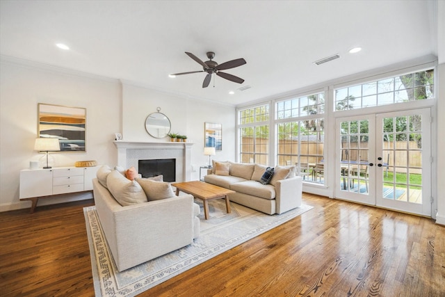 living area featuring a ceiling fan, wood finished floors, french doors, a fireplace, and visible vents