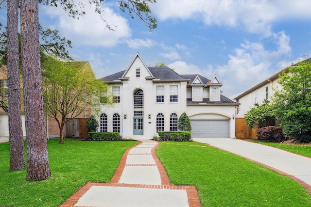 french country style house with driveway, fence, a front yard, a garage, and stucco siding
