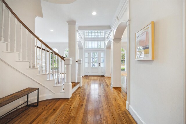 entrance foyer featuring stairway, arched walkways, wood finished floors, and baseboards