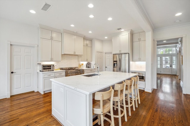 kitchen featuring backsplash, visible vents, stainless steel appliances, and a sink