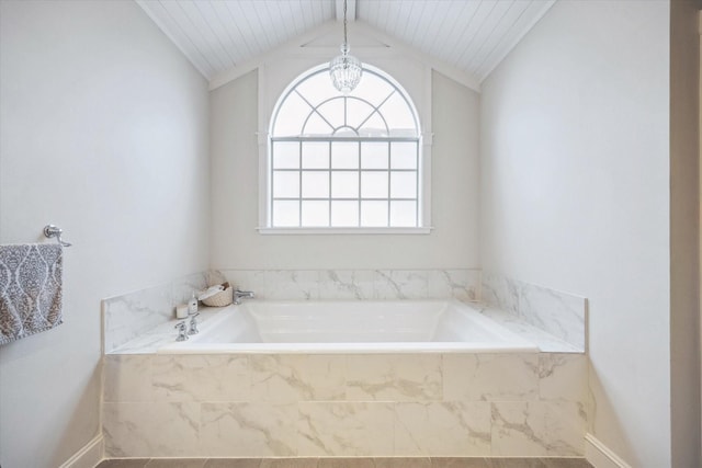 full bathroom featuring a garden tub, baseboards, and vaulted ceiling