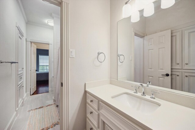 bathroom with baseboards, wood finished floors, vanity, and ornamental molding