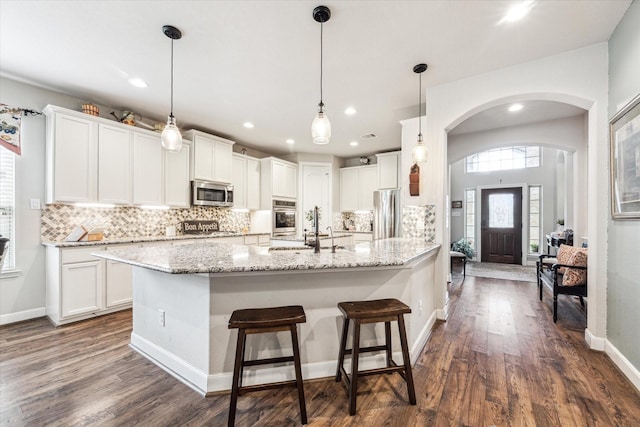 2807 Merlin Ln, Pearland, TX 77581 - kitchen featuring white cabinets, a sink, arched walkways, tasteful backsplash, and appliances with stainless steel finishes