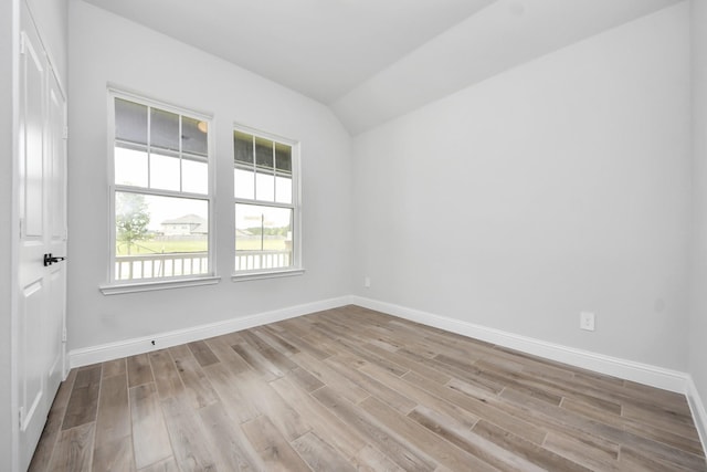 empty room featuring baseboards, wood finished floors, and lofted ceiling