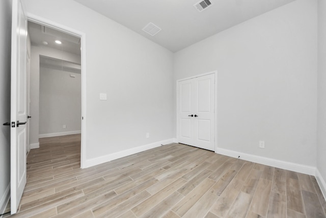 unfurnished room featuring baseboards, light wood-style floors, and visible vents