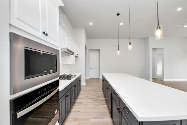 kitchen with light wood-type flooring, white cabinetry, light countertops, a center island, and appliances with stainless steel finishes