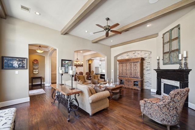 living room with a fireplace, arched walkways, a ceiling fan, beamed ceiling, and visible vents