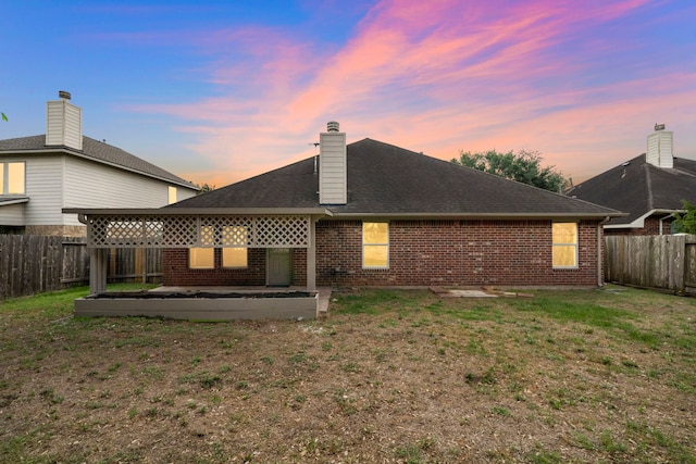 rear view of house featuring a lawn, brick siding, and a fenced backyard