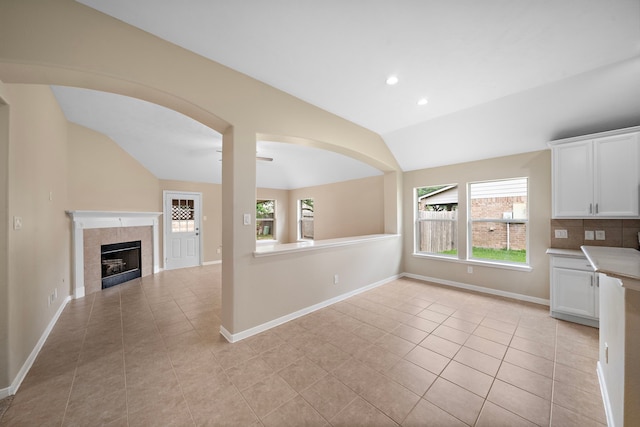 kitchen with lofted ceiling, a wealth of natural light, light tile patterned floors, and white cabinets