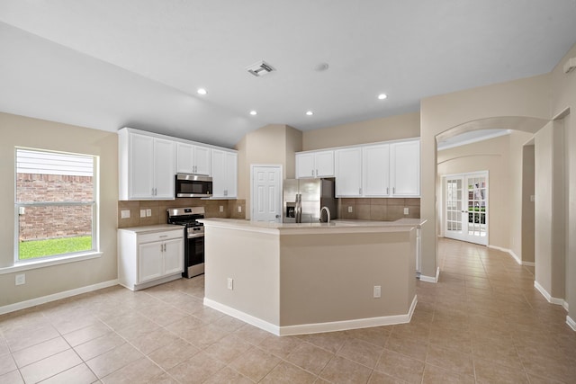 kitchen with light tile patterned floors, backsplash, appliances with stainless steel finishes, and plenty of natural light