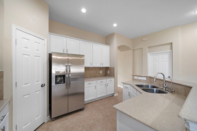 kitchen with white cabinets, stainless steel fridge, decorative backsplash, and a sink