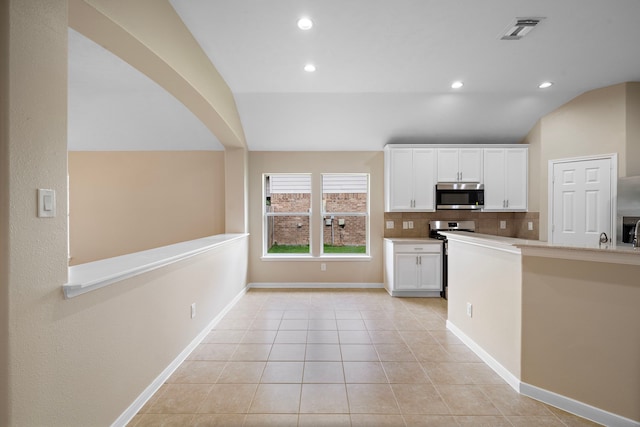 kitchen featuring decorative backsplash, vaulted ceiling, light countertops, white cabinets, and appliances with stainless steel finishes