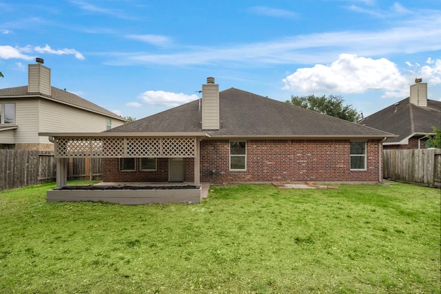 rear view of house featuring brick siding, a fenced backyard, a yard, and roof with shingles