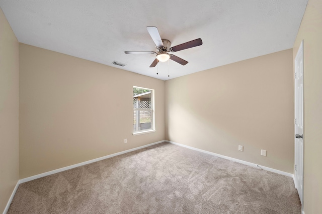 carpeted spare room featuring visible vents, ceiling fan, and baseboards