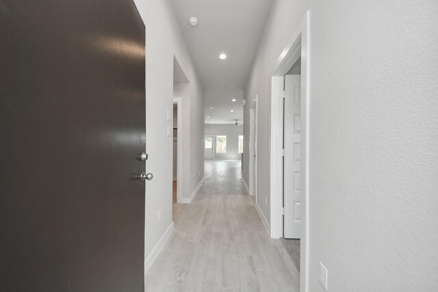 hall featuring light wood finished floors, baseboards, and recessed lighting