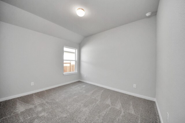 unfurnished room featuring baseboards, lofted ceiling, and carpet flooring
