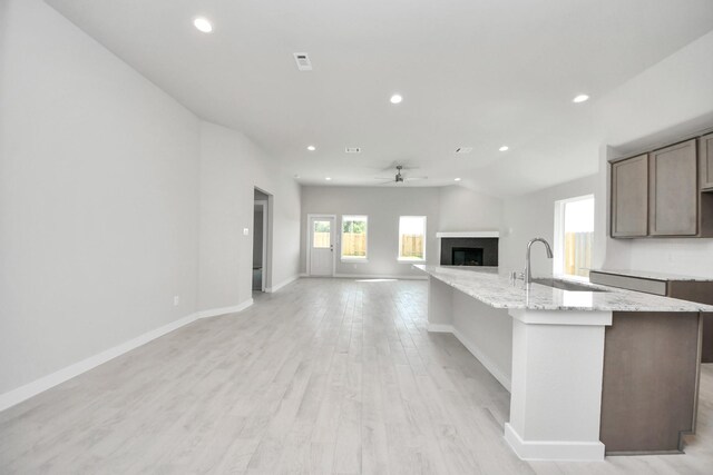 kitchen featuring a ceiling fan, a sink, recessed lighting, and a fireplace