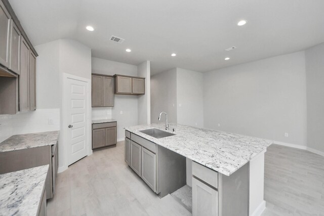 kitchen with a sink, a kitchen island with sink, light wood-type flooring, visible vents, and recessed lighting