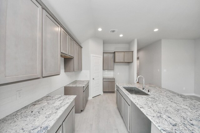 kitchen with visible vents, a sink, recessed lighting, and light stone counters