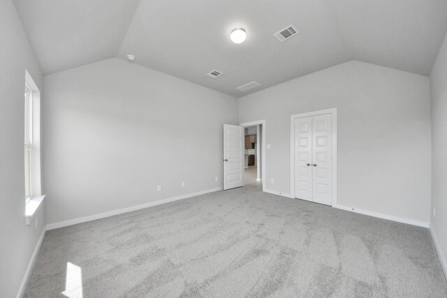 unfurnished bedroom with baseboards, vaulted ceiling, visible vents, and carpet