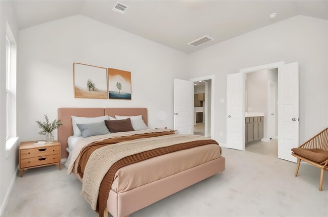 bedroom with lofted ceiling, visible vents, light colored carpet, and ensuite bathroom