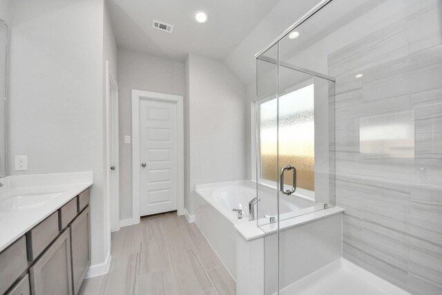 full bathroom featuring a stall shower, visible vents, recessed lighting, a garden tub, and vanity